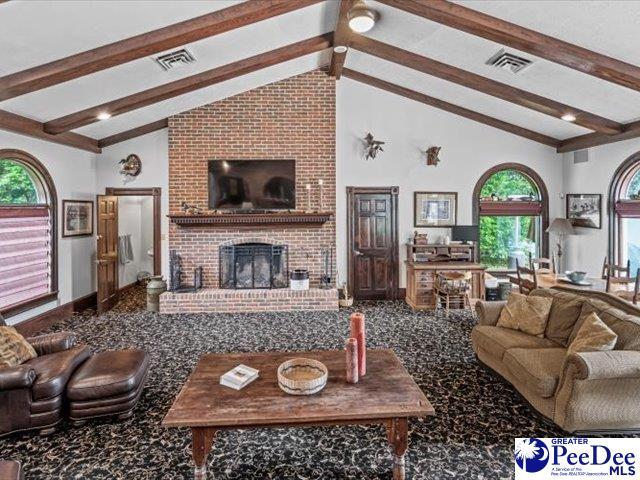 living room with a brick fireplace, high vaulted ceiling, and beamed ceiling