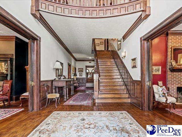 foyer entrance featuring dark wood-type flooring, crown molding, and a brick fireplace