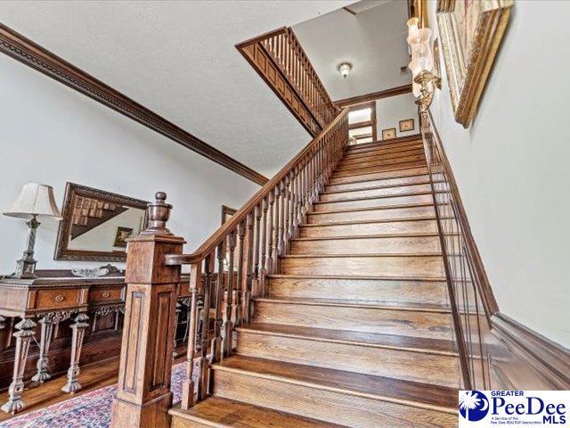 staircase featuring crown molding and wood-type flooring