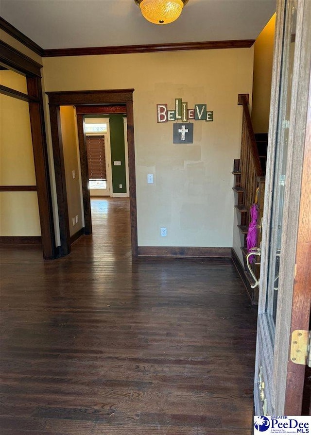 empty room featuring dark wood-style flooring, crown molding, and baseboards