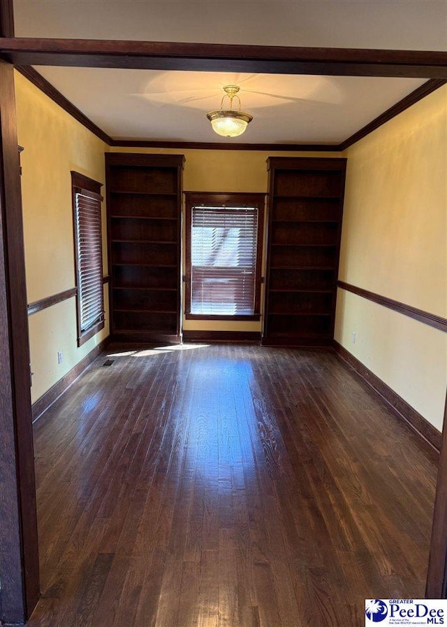 unfurnished room with baseboards, dark wood-type flooring, and crown molding