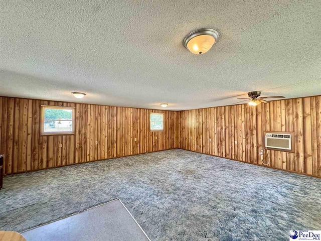 basement with wooden walls, an AC wall unit, plenty of natural light, and carpet