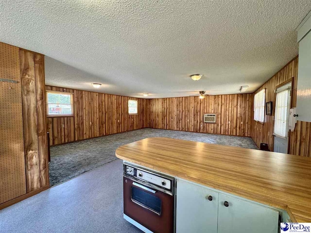 kitchen with oven, an AC wall unit, a textured ceiling, wood walls, and open floor plan