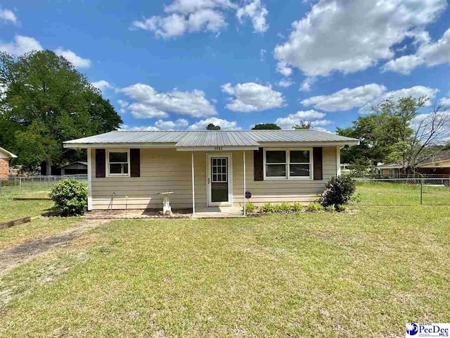 view of front of house featuring fence, metal roof, and a front yard