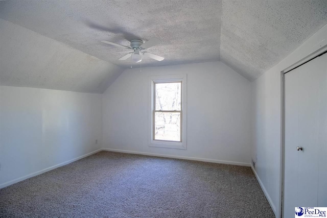 bonus room featuring lofted ceiling, carpet flooring, a textured ceiling, and baseboards