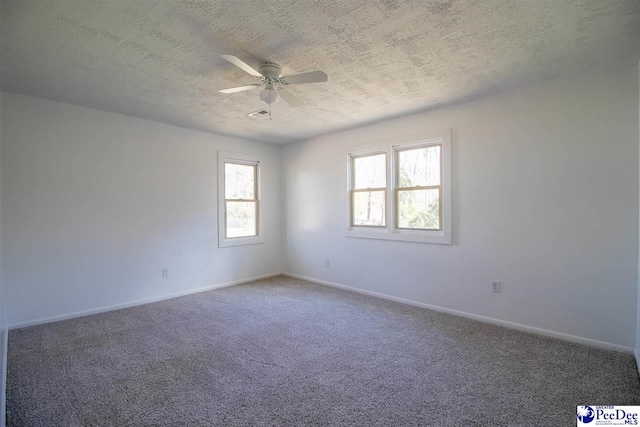 carpeted empty room featuring ceiling fan, a textured ceiling, and baseboards