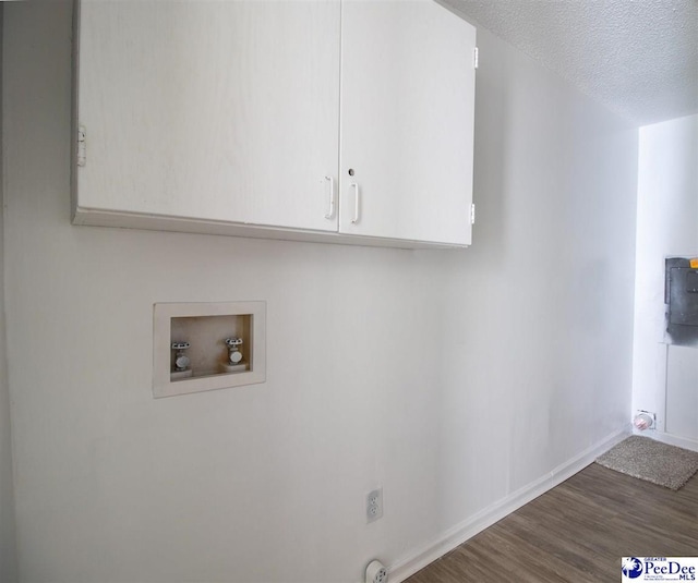 laundry area featuring a textured ceiling, washer hookup, wood finished floors, baseboards, and cabinet space