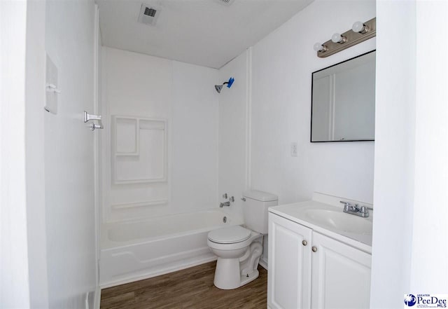 full bathroom featuring toilet, wood finished floors, vanity, visible vents, and washtub / shower combination