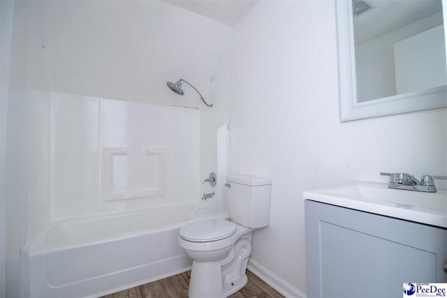 bathroom featuring baseboards, toilet, wood finished floors, bathtub / shower combination, and vanity