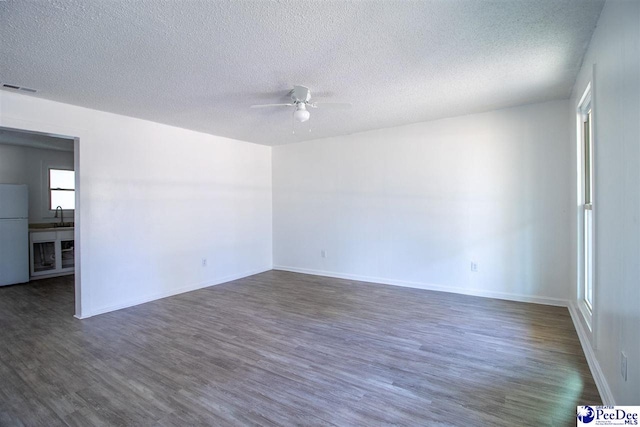 spare room with dark wood-style floors, visible vents, a ceiling fan, a sink, and a textured ceiling