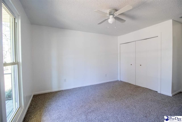 unfurnished bedroom with a textured ceiling, multiple windows, and carpet