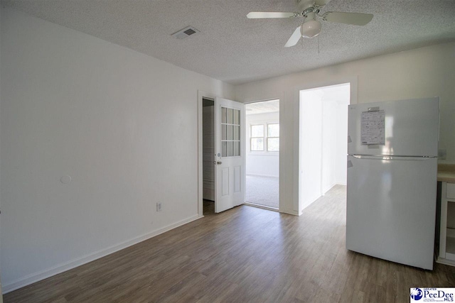 spare room featuring baseboards, a textured ceiling, visible vents, and wood finished floors