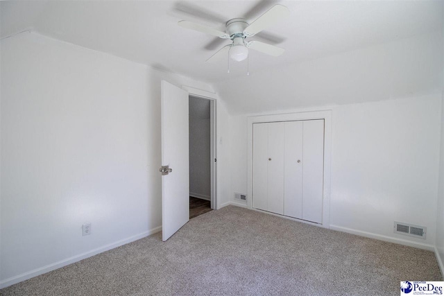 unfurnished bedroom featuring carpet, visible vents, vaulted ceiling, and baseboards