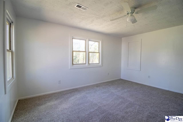 carpeted empty room with a textured ceiling, a ceiling fan, visible vents, and baseboards