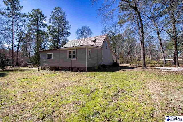 view of property exterior with metal roof and a yard