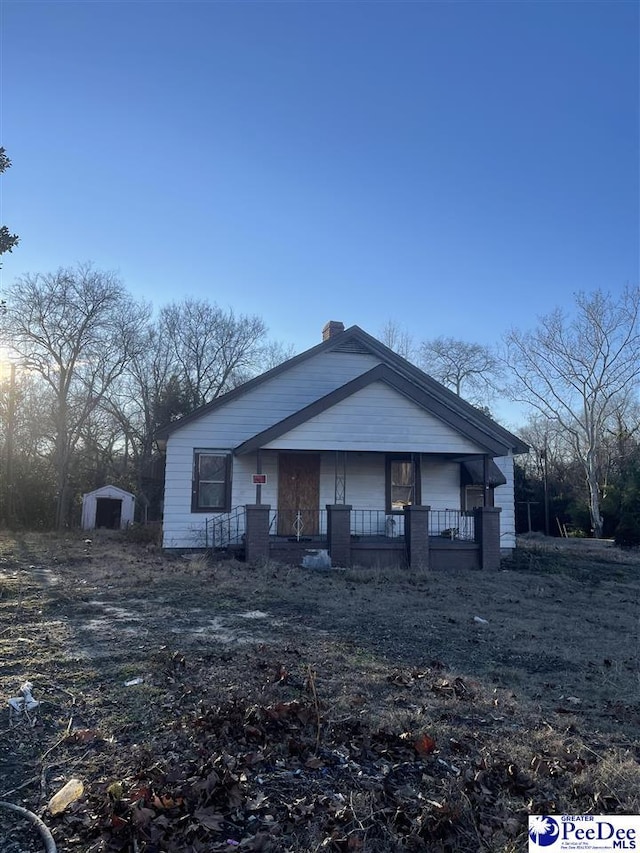 view of front of property featuring a storage unit and covered porch