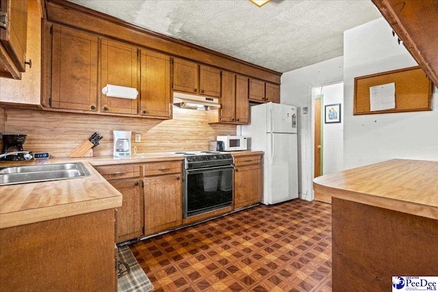 kitchen with white appliances, brown cabinets, light countertops, under cabinet range hood, and a sink