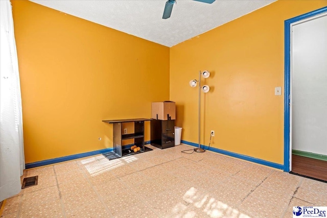 misc room with visible vents, ceiling fan, a textured ceiling, baseboards, and tile patterned floors