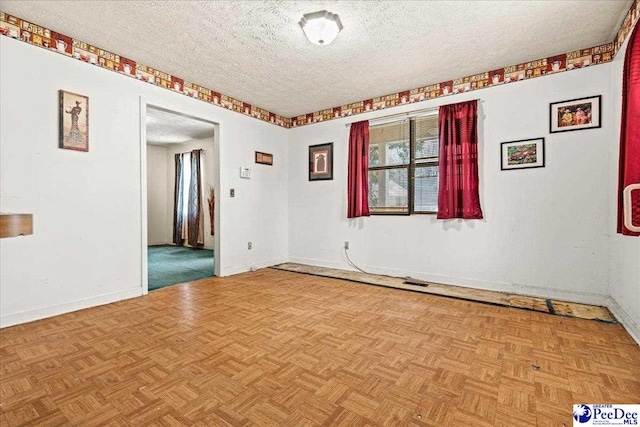 unfurnished room with visible vents, baseboards, and a textured ceiling