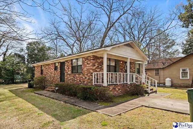 view of front of home featuring brick siding, a porch, and a front yard