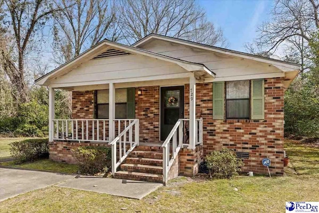 bungalow-style house featuring crawl space, brick siding, and covered porch