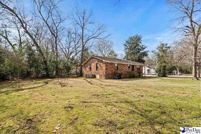 view of property exterior featuring brick siding, a lawn, and central air condition unit