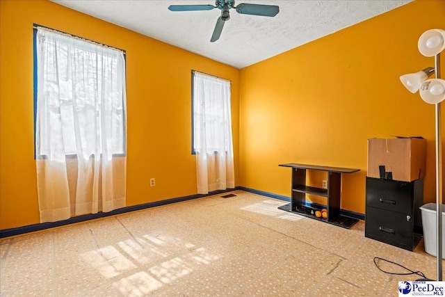 interior space with ceiling fan, a textured ceiling, and baseboards