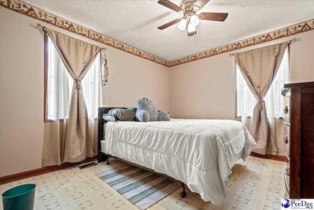 bedroom featuring a textured ceiling, multiple windows, and a ceiling fan