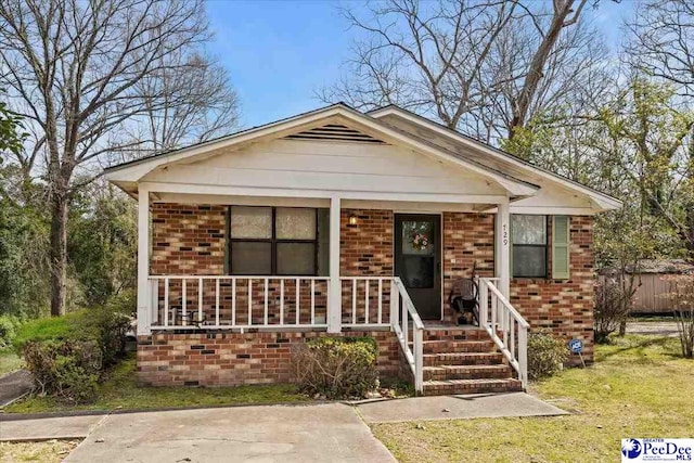 bungalow featuring covered porch and brick siding