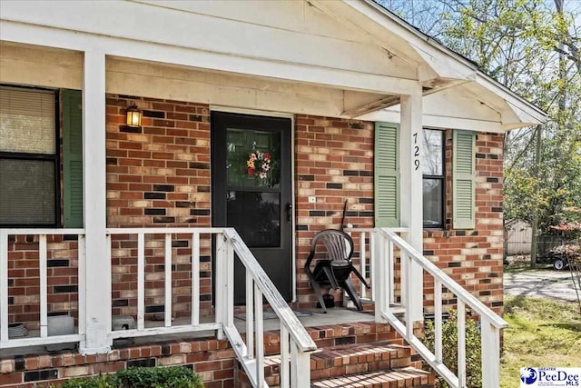 property entrance with brick siding and a porch