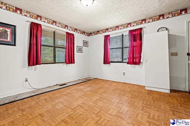 unfurnished room featuring baseboards, visible vents, and a textured ceiling