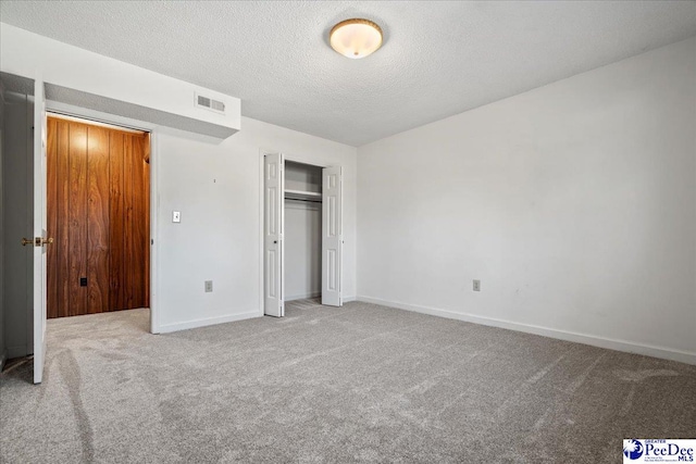 unfurnished bedroom featuring baseboards, visible vents, carpet, a textured ceiling, and a closet