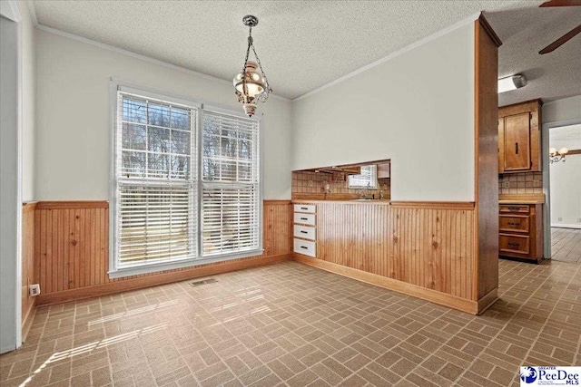 interior space featuring a wainscoted wall, visible vents, brick patterned floor, and wood walls