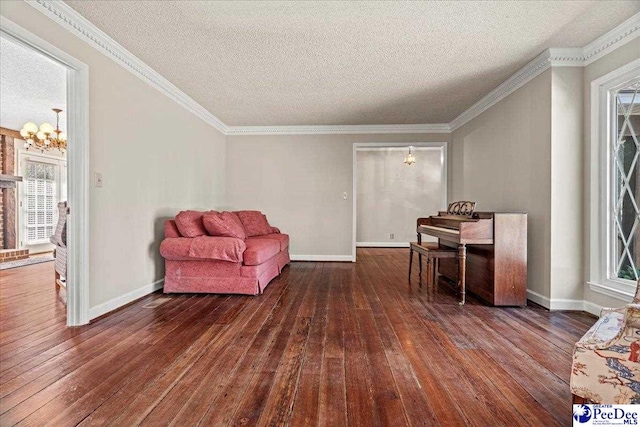 living area with baseboards, crown molding, a notable chandelier, and hardwood / wood-style floors