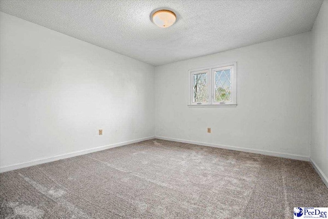 spare room with carpet floors, baseboards, and a textured ceiling