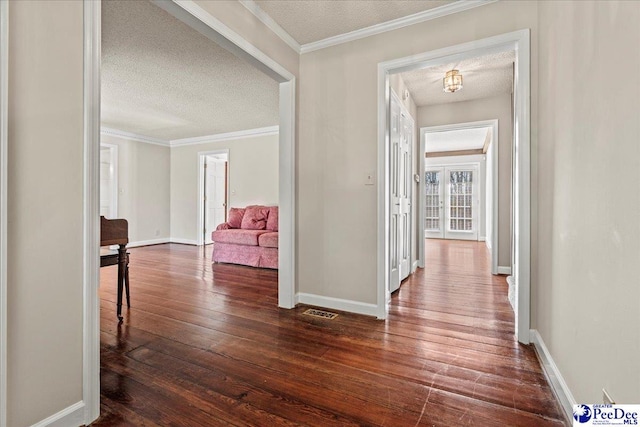 corridor featuring dark wood-type flooring, crown molding, a textured ceiling, and baseboards