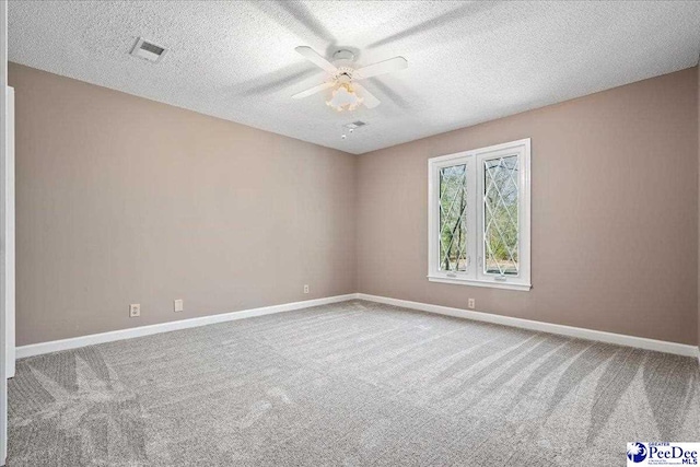 spare room featuring visible vents, baseboards, ceiling fan, carpet, and a textured ceiling