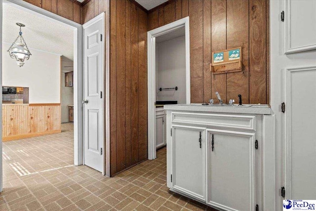 kitchen with brick floor, wooden walls, and white cabinets