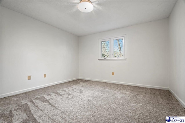 carpeted empty room with baseboards and a textured ceiling