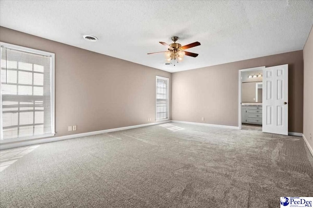 carpeted spare room with a ceiling fan, visible vents, a textured ceiling, and baseboards