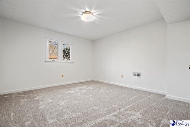 empty room featuring a textured ceiling, carpet, visible vents, and baseboards