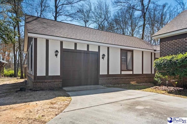 exterior space with a garage, concrete driveway, a shingled roof, and brick siding