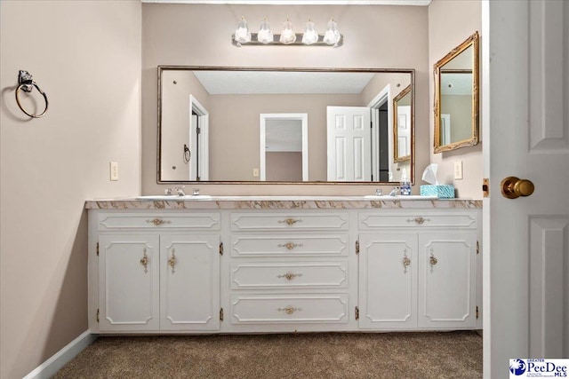 bathroom with a sink, baseboards, and double vanity