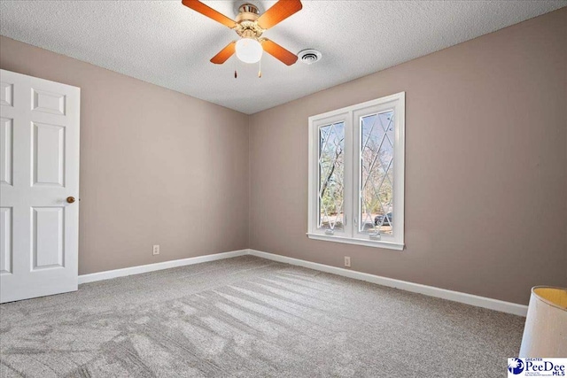 carpeted empty room featuring a ceiling fan, visible vents, a textured ceiling, and baseboards