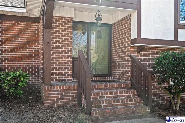 view of exterior entry featuring brick siding