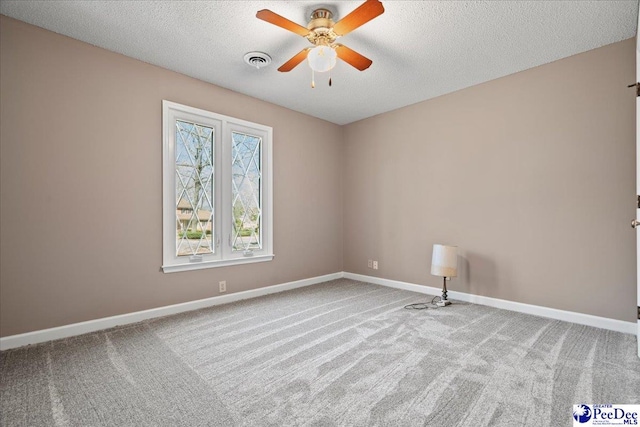 carpeted spare room with a ceiling fan, baseboards, visible vents, and a textured ceiling