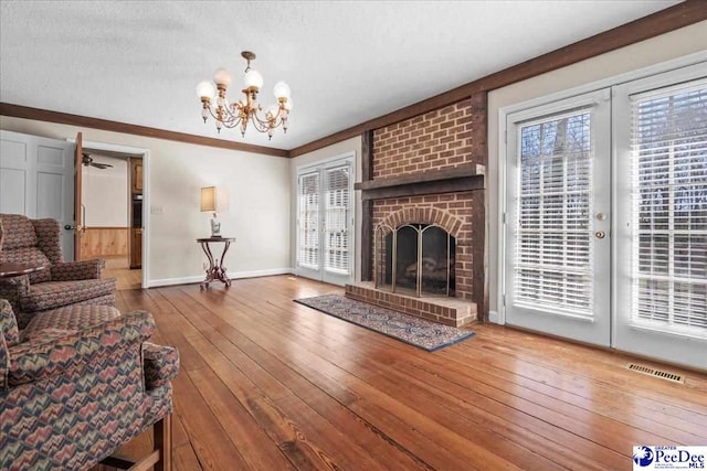 living area featuring visible vents, baseboards, wood-type flooring, a textured ceiling, and a fireplace