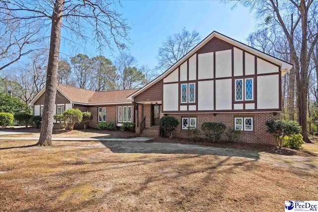 tudor-style house featuring a front yard and brick siding