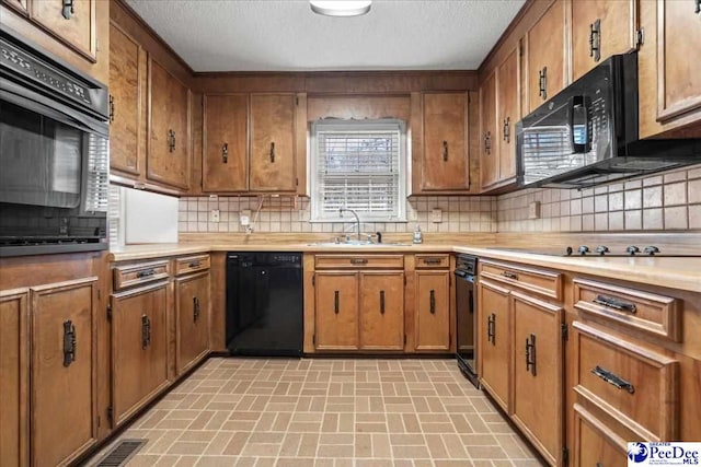 kitchen featuring black appliances, brown cabinetry, and a sink