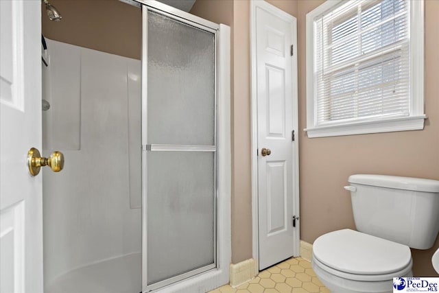 full bathroom with toilet, a shower stall, and baseboards